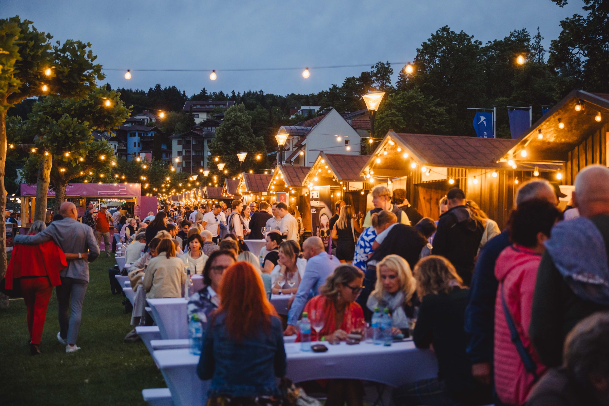 Beleuchtete WeinWiesn mit Besuchern am Abend